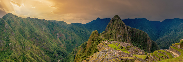 Panoramic view of Machu Picchu ruins in Peru. Behind we can appreciate big and beautiful mountains full of green vegetation. Archaeological site, UNESCO World Heritage