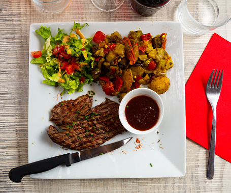 Appetizing grilled veal entrecote with side dish of fresh and sauteed vegetables and tomato sauce