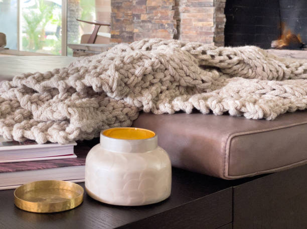Warm, comfy living room setting with candle and chunky afgan with thick gray yarn. stock photo