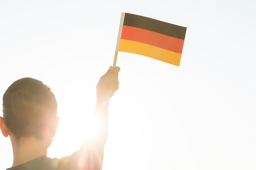 Back view of woman holding German flag in hand.