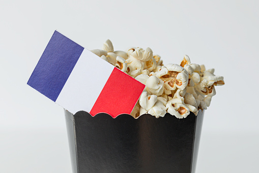 Black popcorn bag in front of white background with French flag. Representing film industry in France.