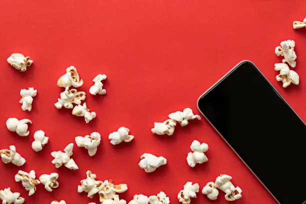 Popcorn pattern and smart phone on red background.