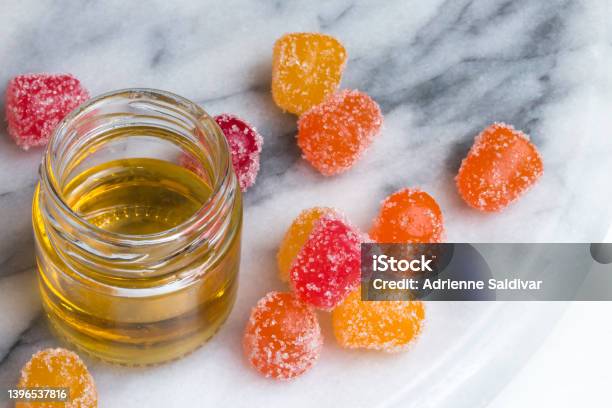 Cbd Gummy Candy Gumdrops And Oil On A White Marble Surface Stock Photo - Download Image Now