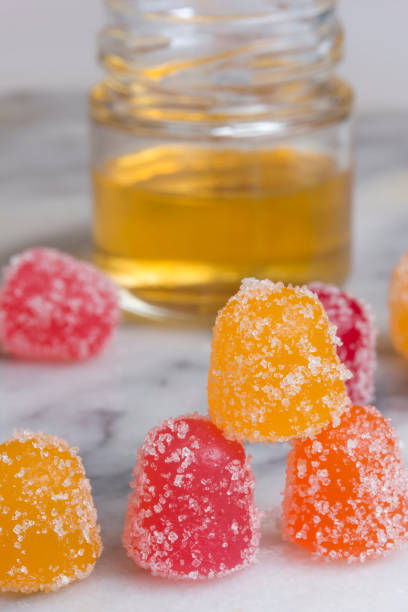 CBD gummy candy gumdrops and oil on a marbled surface stock photo