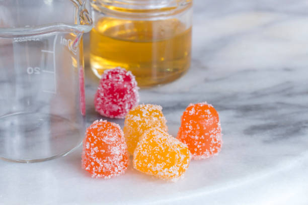 CBD gummy candy gumdrops and oil on a white marble surface stock photo