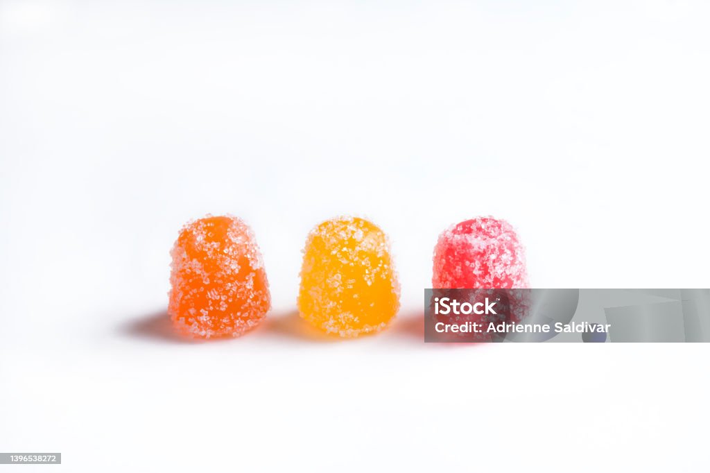 Three CBD gummy candy gumdrops on a white background Three gummy candy gumdrops arranged in a row in red, orange, and yellow, isolated on a white background. Vitamin health supplement or CBD edibles. Cannabis Plant Stock Photo