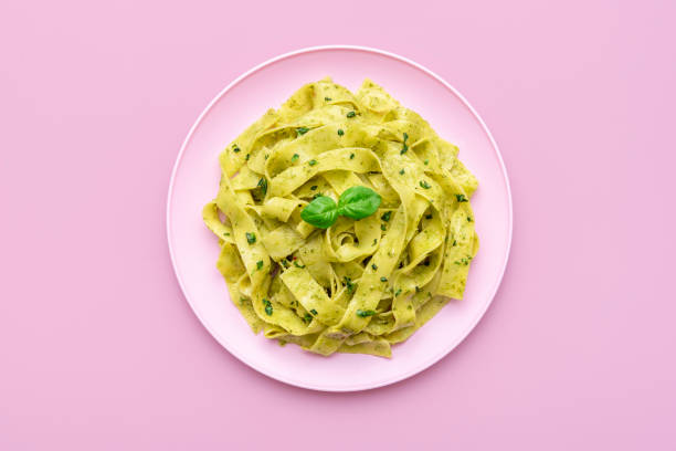 pasta mit pestosauce minimalistisch auf rosa grund - vegan food stock-fotos und bilder