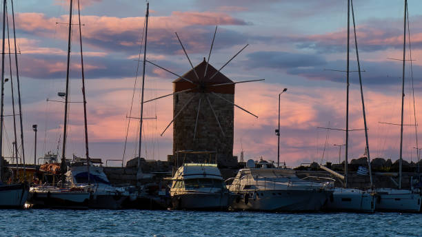 istock Windmills in Mandraki Harbor at sunset time. 1396541334