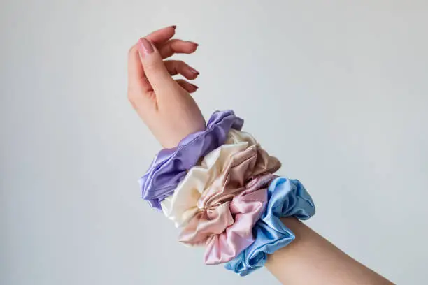 Photo of Silk elastic bands on woman's arm. Luxury colors.