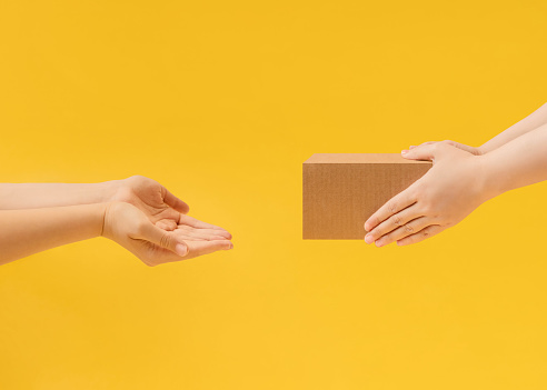 Hands handing over a parcel in a cardboard box