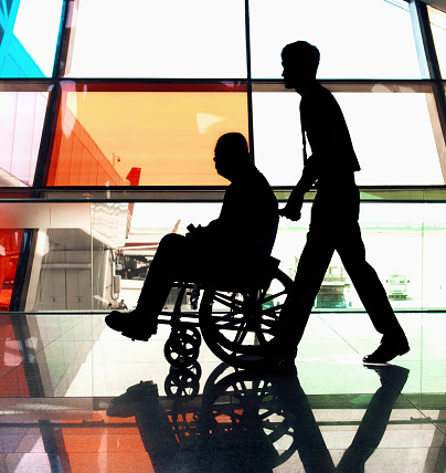 Man in wheelchair being assisted by staff member in facility