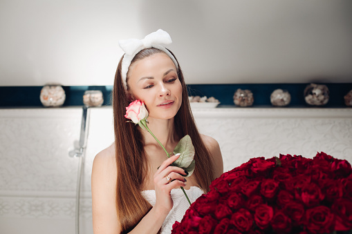 Woman hands holding red roses in bathtub with milk.