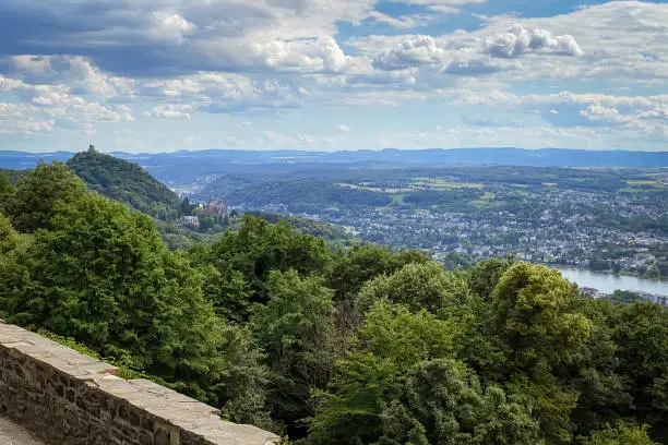Scenic view from Petersberg mountain at Siebengebirge mountain range in Germany overlooking Drachenburg castle, river Rhine and Bad Godesberg, a district of the city of Bonn against blue sky with clouds