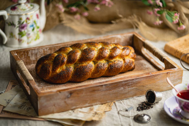 zbliżenie bochenka chleba challah z makiem na wierzchu na drewnianej tacy z zabytkowymi papierami - hanukkah loaf of bread food bread zdjęcia i obrazy z banku zdjęć