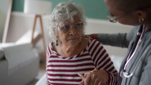 Nurse helping a senior woman standing in the bedroom