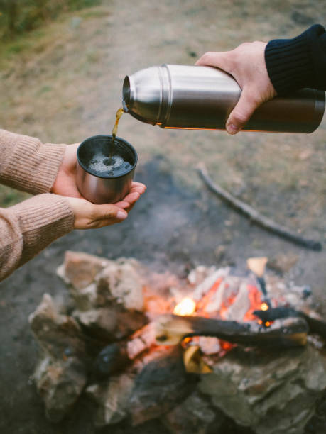 istock a man pours tea from a thermos near a fire 1396553644