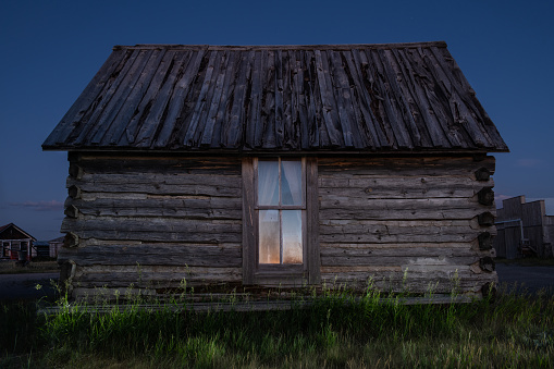 Old log cabins dot the countryside of South Dakota, illuminated in United States, South Dakota, Custer