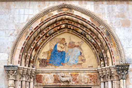 This mosaic below the Assumption of the Virgin on the tympanum of the Porta della Mandorla (Almond Gate), depicts the Coronation of the Virgin, showing the Virgin Mary being crowned by Christ as a symbol of her exalted status in heaven. The gold halo signifies the sacred and divine nature of the figures depicted. The white dove above her represents the Holy Spirit. The mosaic lunette was created by Domenico and Davide Ghirlandaio in the late 15th century.