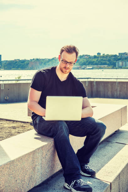 istock Young man working on laptop computer outdoors in New York City 1396560262