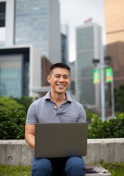 istock Asian man using laptop outdoors Hong Kong 1396565118