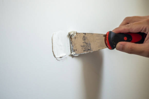 man repairing crack white wall with spatula - plasterer plaster wall dirty imagens e fotografias de stock