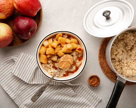 Apple cinnamon pie oatmeal porridge bowl on grey concrete background, table top view copy space for design elements or text