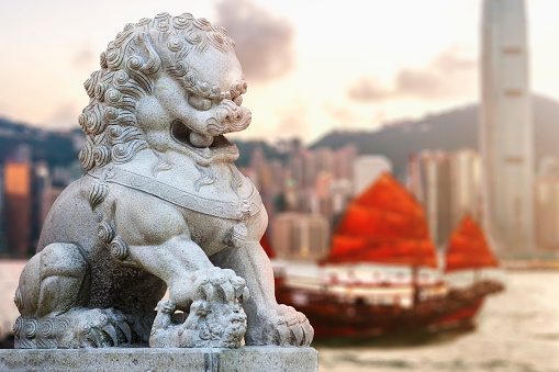 Chinese Temple Foo Dog Lion guard statue with Hong Kong harbor and red sail junk boat, China