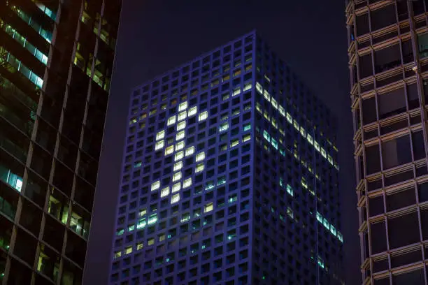 Photo of Dollar money shape in lights in downtown district office business buildings at night