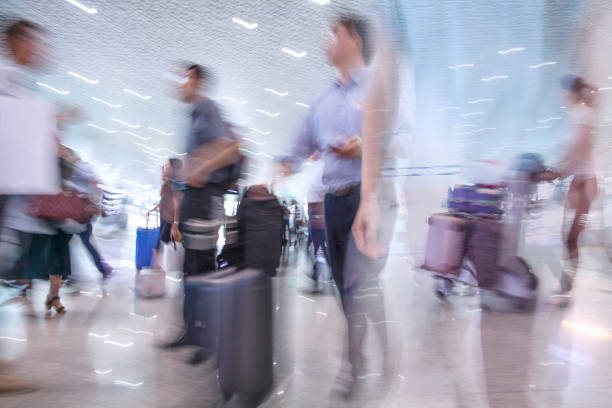 Blurred passengers moving through airport terminal while traveling with luggage, Bao’an International Airport, Shenzhen, China