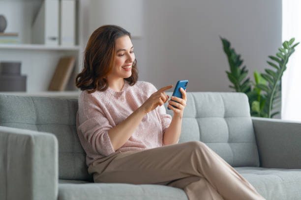 istock woman is using a phone sitting on a sofa 1396585124