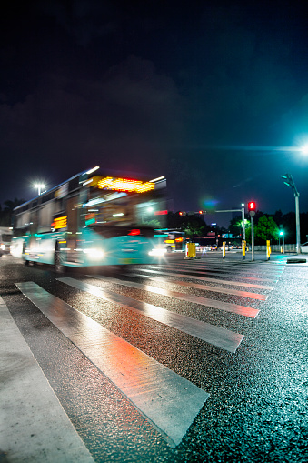 Blurred public transportation bus passing on city street at night