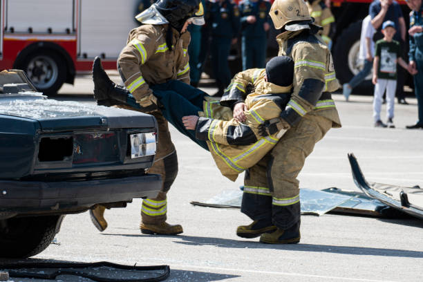 first aid after an accident on the road. rescuers break down car that got into an accident on the road. rescue of the driver and passenger after an accident. - lifeguard association imagens e fotografias de stock