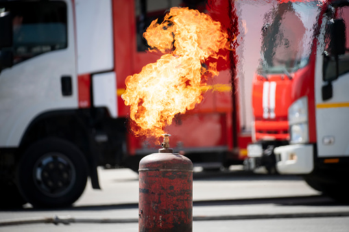 LPG tank on fire. a burning metal gas cylinder on the background of a fire truck. Explosive situation.