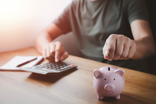A man hand putting coins in pink piggy bank for account save money. Planning step up, saving money for future plan, retirement fund. Business investment-finance accounting concept.