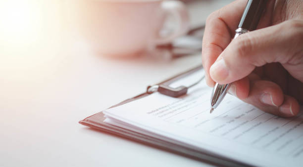 istock Close-up of Hand using writing pen with questionnaire or paperwork survey question filling 1396591552
