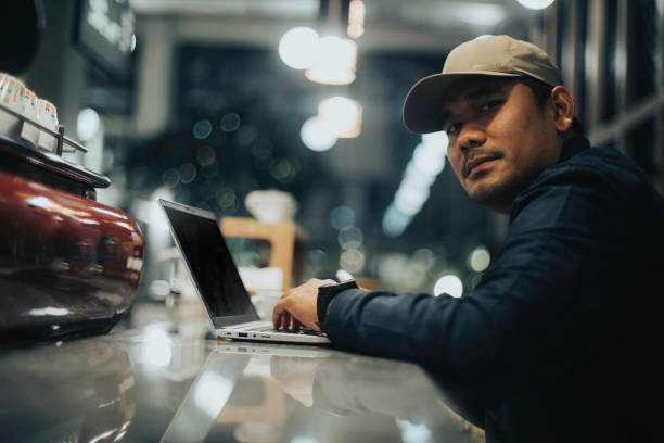 mężczyzna z azji południowo-wschodniej siedzący w kawiarni, pracujący - southeast asian ethnicity men laptop image type zdjęcia i obrazy z banku zdjęć