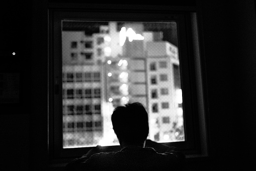 Image of a person looking out the window at night ,Monochrome