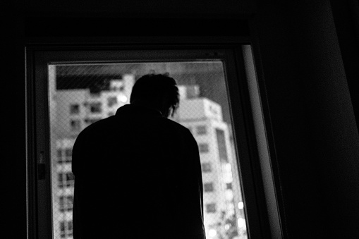 Image of a person looking out the window at night ,Monochrome