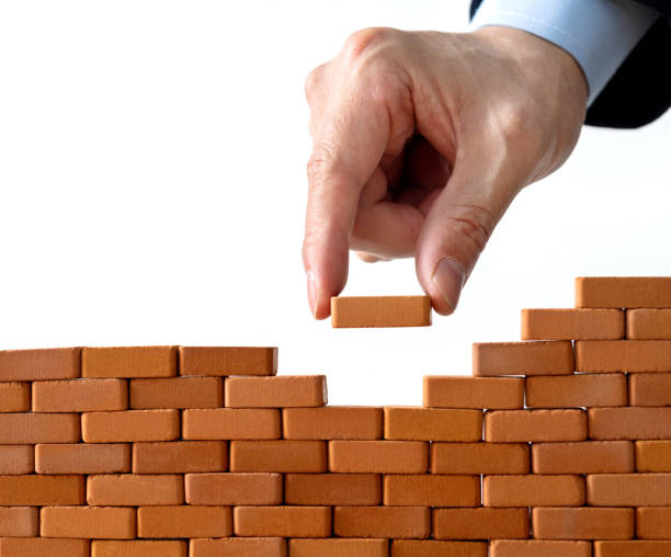 istock Businessman putting toy brick onto a wall 1396594527