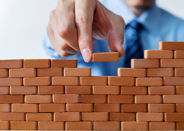 istock Businessman putting toy brick onto a wall 1396594539