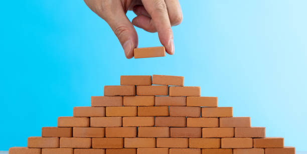 istock Man putting toy brick onto a pyramid 1396594541