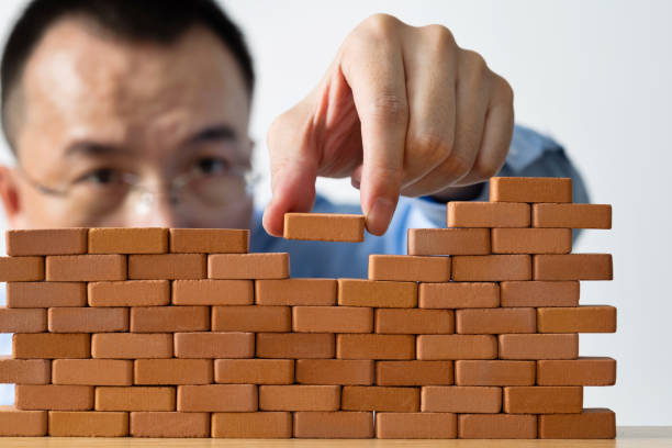 istock Businessman putting toy brick onto a wall 1396594546