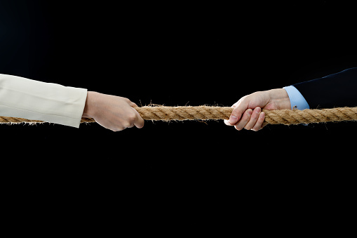 Two business person playing tug-of-war.