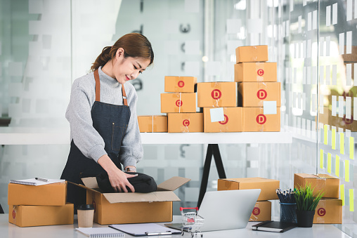 Portrait of a Startup, Small Business, SME Owner, Female Entrepreneur Packing in boxes, working on parcel boxes. Receipts and online order checks to prepare the boxes. Sell 