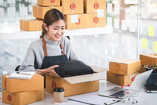 Portrait of a Startup, Small Business, SME Owner, Female Entrepreneur Packing in boxes, working on parcel boxes. Receipts and online order checks to prepare the boxes. Sell 