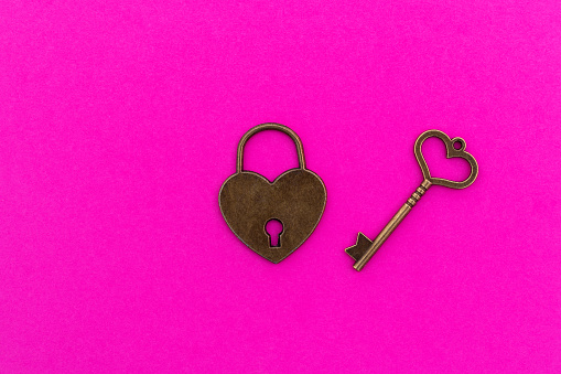 Heart shaped key and lock on red background.