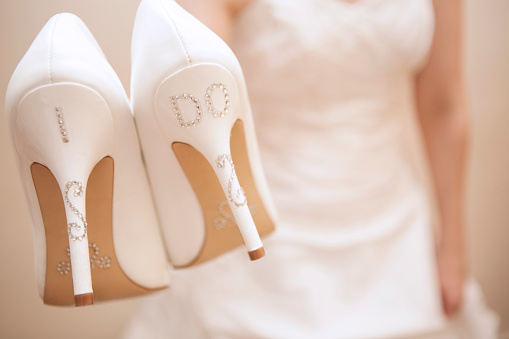 Unrecognizable bride holding wedding shoes