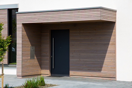 Beautiful entrance to a new residential house with modern front door and wooden panels