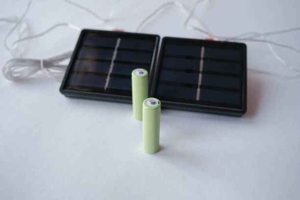 istock rechargeable batteries and mini solar panel. AA battery charger based on solar panels. free solar power for small green projects 1396604310