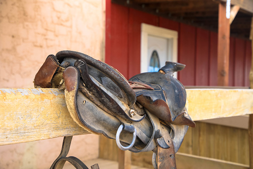 An old leather saddle on a wooden fence.